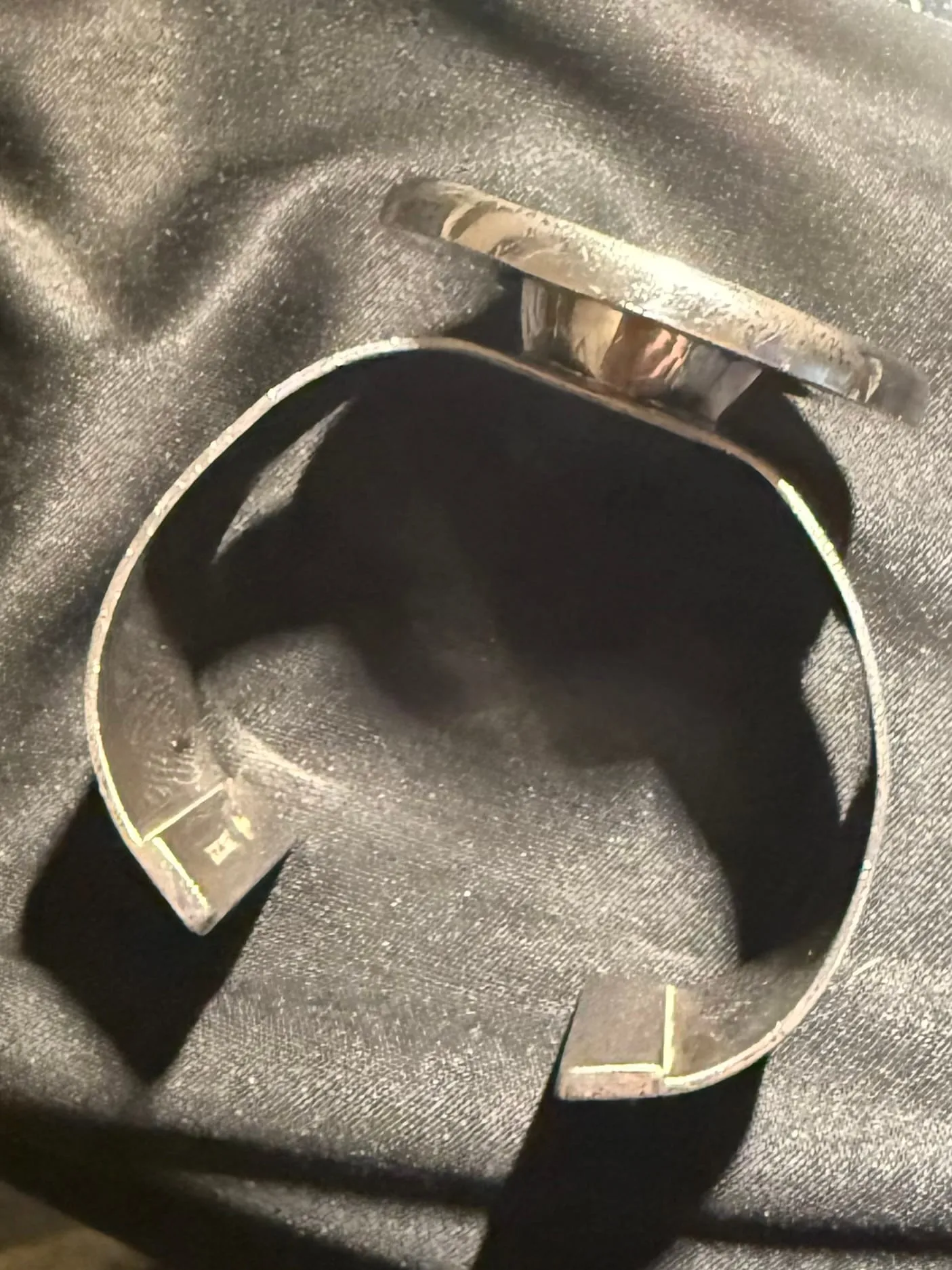 A silver cuff bracelet set with an embedded hologram.