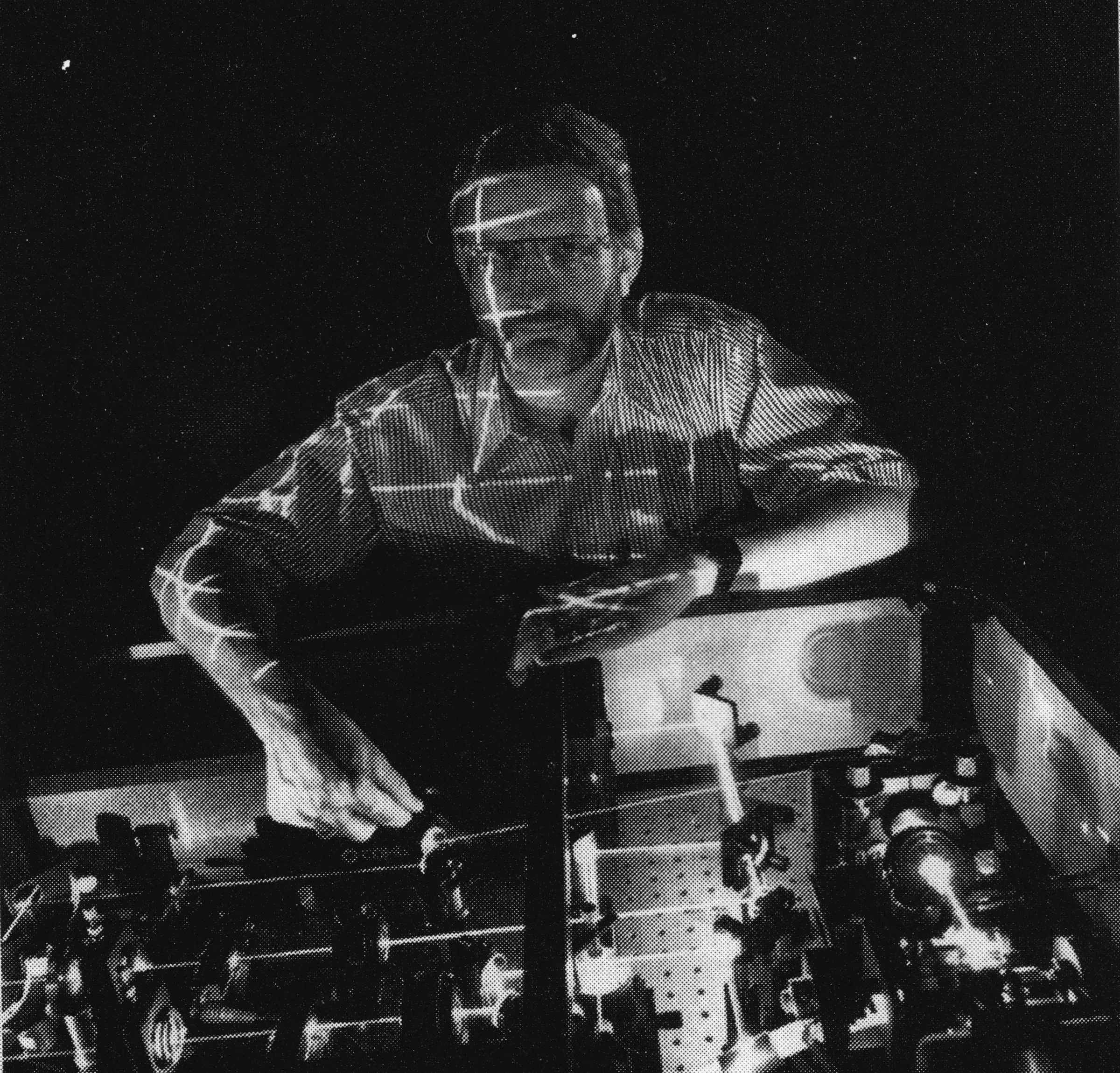 Paul Linden leans over his laser optical bench as laser beams cross in front of him, photographed for a 1997 Kansas Alumni magazine profile of his laser video projection work.